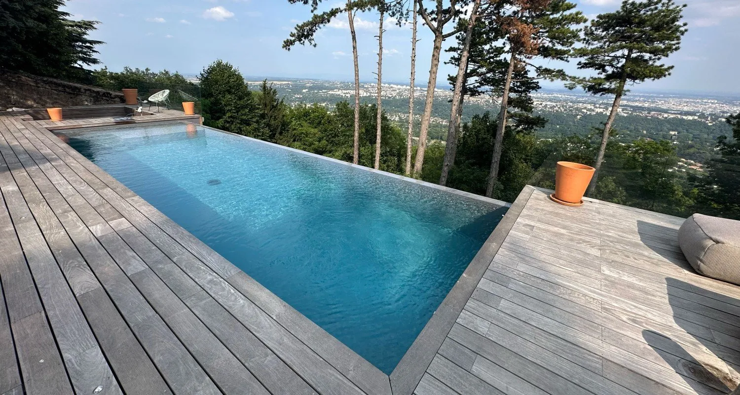 Piscine à débordement avec terrasse en bois et vue dégagée